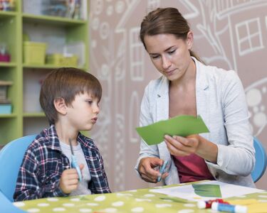 teacher-cutting-paper-for-boy